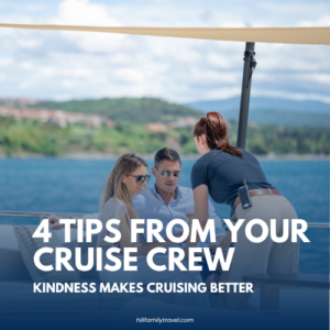 Cruise crew member speaking with guests on an outdoor deck with ocean and coastline in the background.