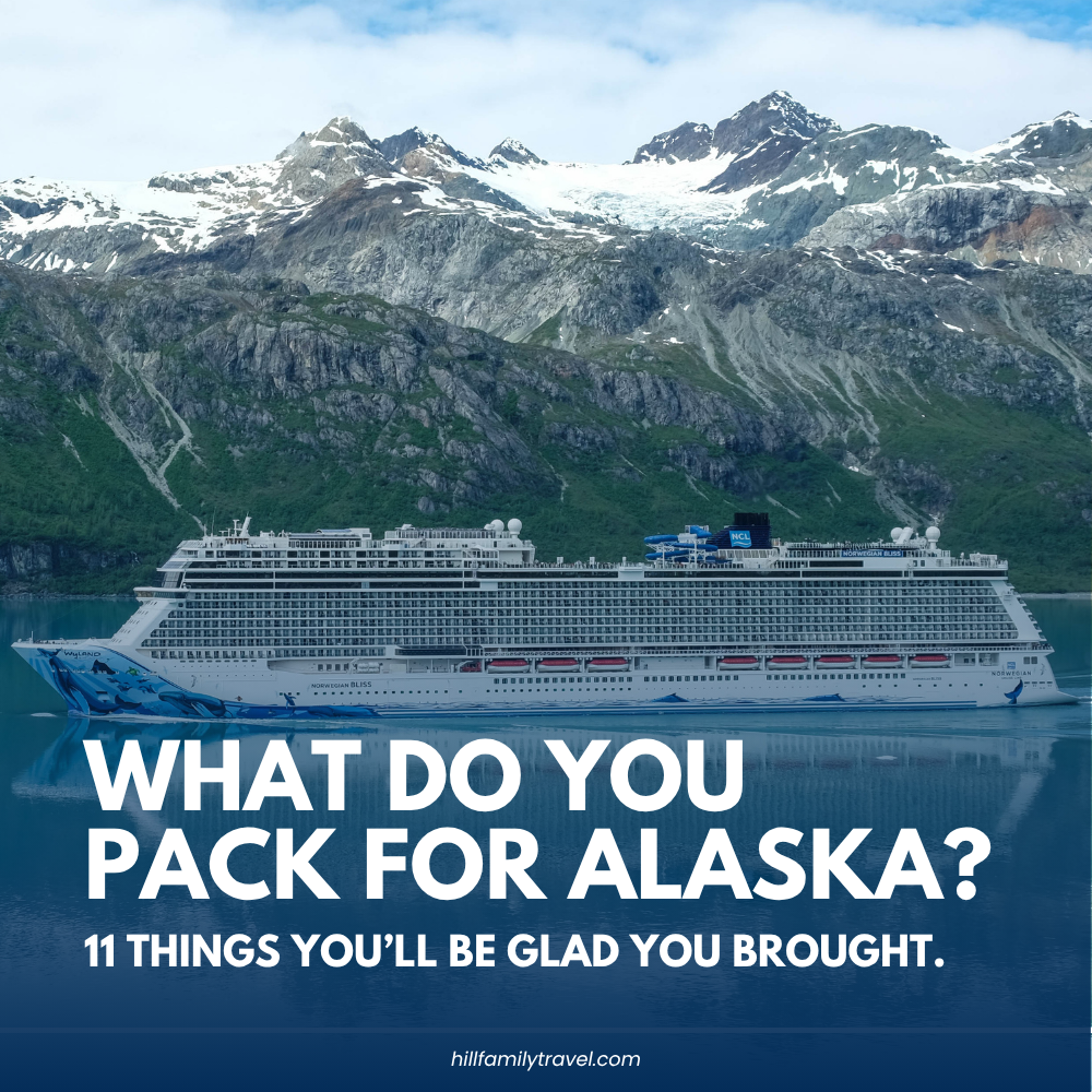 Norwegian cruise ship sailing beneath snow-covered mountains in Alaska for an Alaska cruise packing guide.